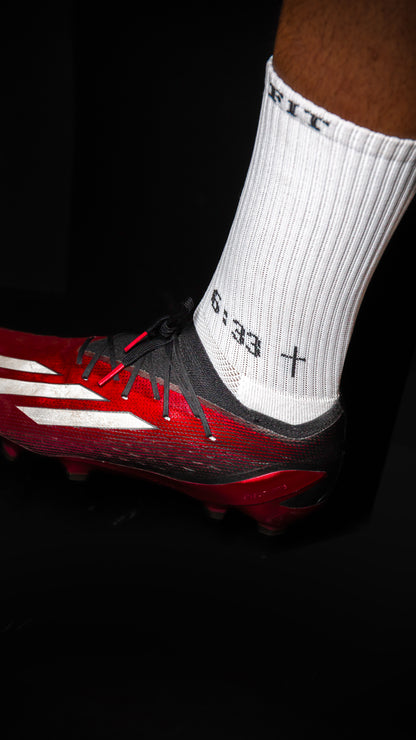 Close-up of white performance socks with grip dots and soccer cleats